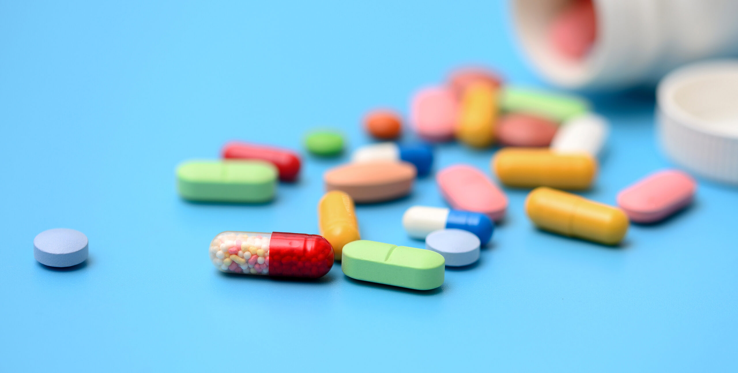 Colorful Pills scattered from white plastic pills bottle